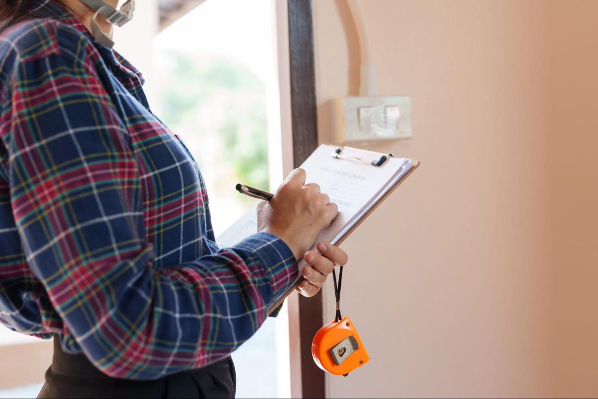 Een expert noteert details op een checklist tijdens een plaatsbeschrijving van de woning